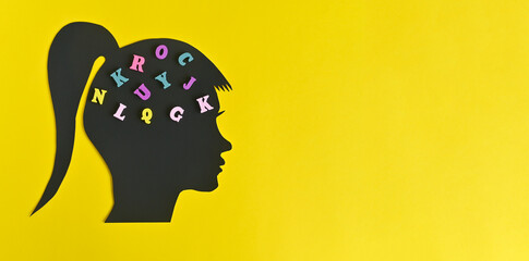Silhouette of a woman's head with letters in the brain. on a yellow background. concept with copy...