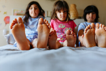 barefeet of three children lying on the bed