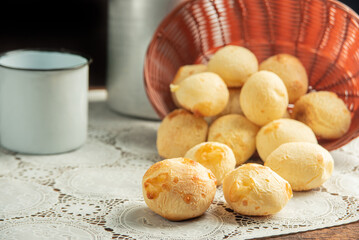 Cheese bread, Basket with cheese bread lying on a white lace tablecloth and accessories, dark background, selective focus.