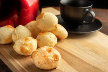 Cheese bread, Basket with cheese bread lying on rustic wood, red kettle and accessories, dark background, selective focus.