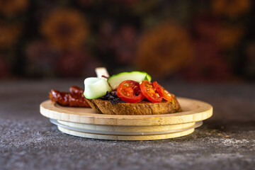 close-up of black bread bruschetta with tomato and cucumber on a wooden plate
