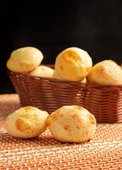 Cheese bread, Basket with cheese bread lying on a wooden woven mat, dark background, selective focus.