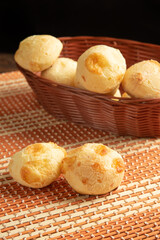 Cheese bread, Basket with cheese bread lying on a wooden woven mat, dark background, selective focus.