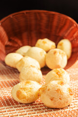 Cheese bread, Basket with cheese bread lying on a wooden woven mat, dark background, selective focus.