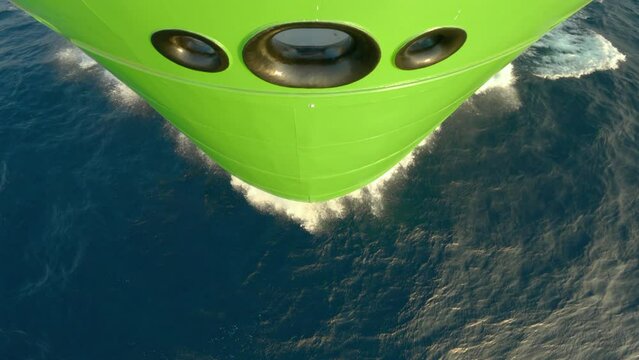 Bow of ship cuts waves. Green side vessel powered by natural gas. Top down close up bow view