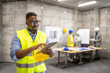 Structural engineer working on digital tablet at construction site.