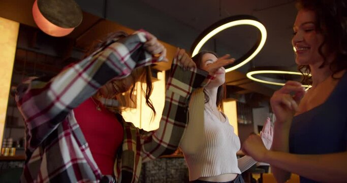 Dance Extravaganza: Three Joyful Girls Grooving at a Sunlit Cafe-Bar Bachelorette Party