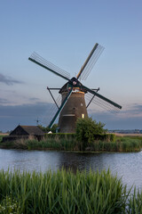 Beautiful wooden windmills at sunset in the Dutch village of Kinderdijk. Windmills run on the wind. The beautiful Dutch canals are filled with water. Beautiful sunset. - 611777371