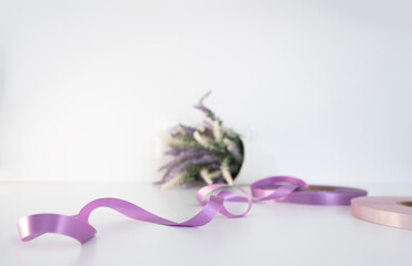Two coils of satin ribbon for labels or branding lilac and purple colors. Clothing production.