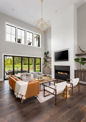Living room in new luxury home with chandelier, floor-to-ceiling fireplace surround, built-in...