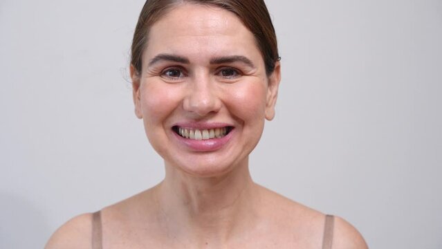 Close-up middle-aged woman putting on transparent aligners on the upper jaw Dental care and dentistry orthodontic concept