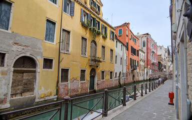 Fototapeta na wymiar Venice Canal View with Stone Walkway and Distant Bridge