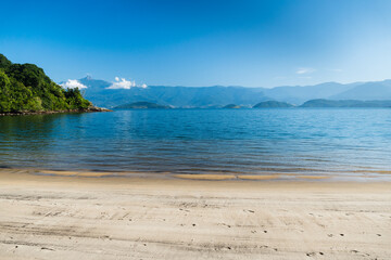 Beautiful beach in Angra do Reis, green coast of Rio de Janeiro. Tanguá Beach. Hills and mountains in the background on a sunny day. Crystal clear water.