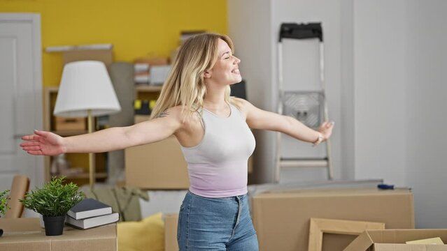 Young blonde woman smiling confident turning by herself with arms open at new home