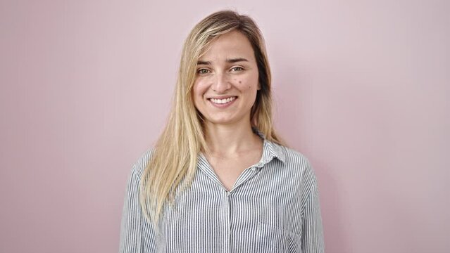 Young blonde woman smiling confident saying yes with head over isolated pink background
