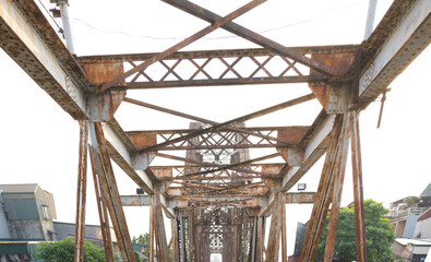 Vintage steel train bridge at Long Bien railway through a river in Downtown Hanoi, Vietnam. Urban city town.