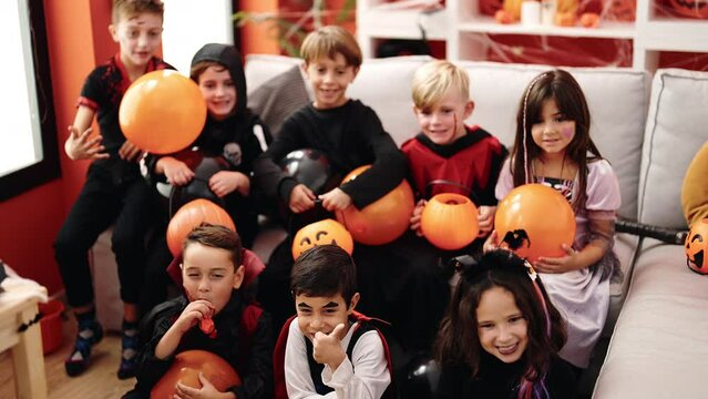 Group of kids wearing halloween costume holding balloons at home