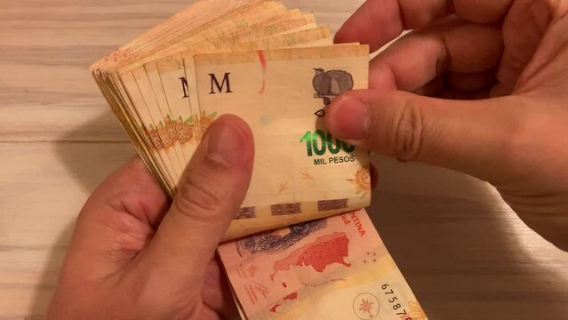 hands counting money Argentine 1000 peso bills, symbol for Argentina's inflation