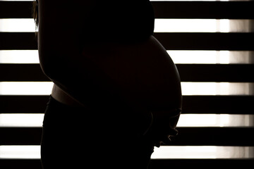pregnant woman close up backlit. unwanted pregnancy concept