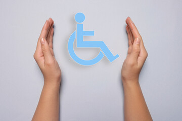 Disability inclusion. Woman protecting wheelchair symbol on light background, closeup