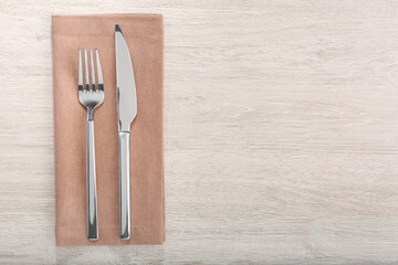 Shiny fork, knife and napkin on white wooden table, flat lay. Space for text