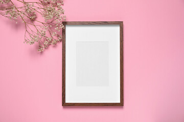 Empty photo frame and gypsophila flowers on pink background, flat lay. Space for design