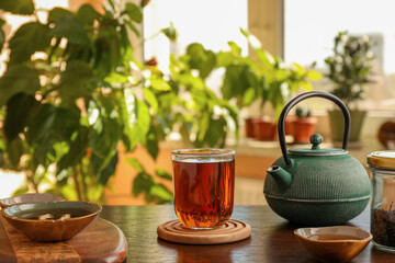 Teapot and cups of freshly brewed tea on wooden table indoors. Traditional ceremony