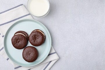 Tasty sweet choco pies and glass of milk on light gray table, flat lay. Space for text