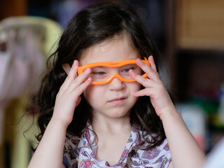 cute young girl playing with toy 3D glasses while in her pajamas