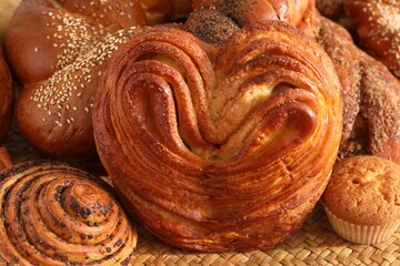 Different tasty freshly baked pastries on wicker mat, closeup