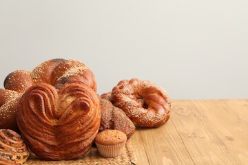 Different tasty freshly baked pastries on wooden table, space for text