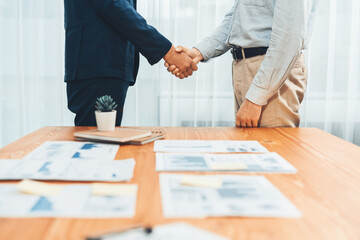 Two businesspeople shake hand after signing contract document to merge their partnerships in...