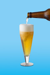 beer glass, the beer bottle fills the glass, on blue background
