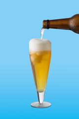 beer glass, the beer bottle fills the glass, on blue background