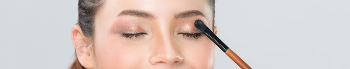 Closeup beautiful girl with flawless applying glamorous eye shadow makeup with eyeliner brush....