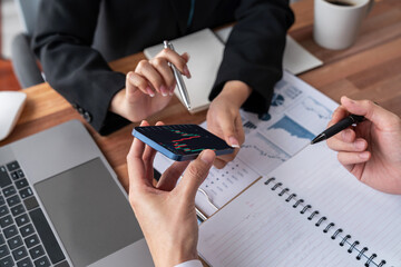 Risk management or financial team working and analyzing on client's portfolio while monitoring stock graphs on smartphone screen. Stock investment company with data analysis in office. Jubilant