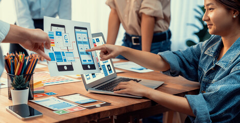 Panorama shot of front-end developer team brainstorming UI and UX designs for mobile app on paper...