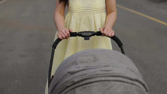 mother pushing infant baby stroller and walking in the park