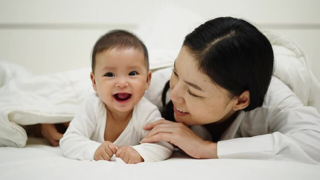 happy mother and infant baby lying prone on a bed

