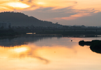 Fototapeta premium Aerial view of the river with the islets next to it, at dawn with golden sunlight and the reflection of the cloudy sky on the river.