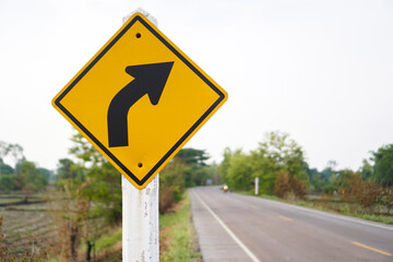 A traffic sign that is a warning sign on the right curve and has a road as a background concept...