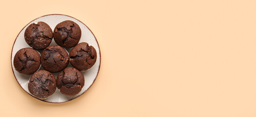 Plate with tasty chocolate muffins on beige background with space for text