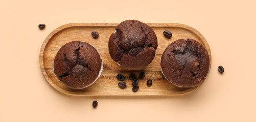 Plate with tasty chocolate muffins and coffee beans on beige background