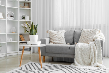 Comfortable sofa with cushions in interior of light living room