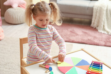 Cute little girl playing matching game with clothespins at home