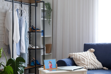 Shelving unit with clothes in interior of light room