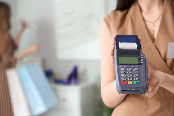 Female sales assistant with payment terminal in shoe shop, closeup
