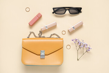 Sunglasses, purse, lipsticks, gypsophila flowers and jewellery on yellow background