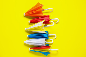 Different mini umbrellas on yellow background