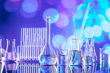 Laboratory investigations. Glass tubes and beakers on blue bokeh background.